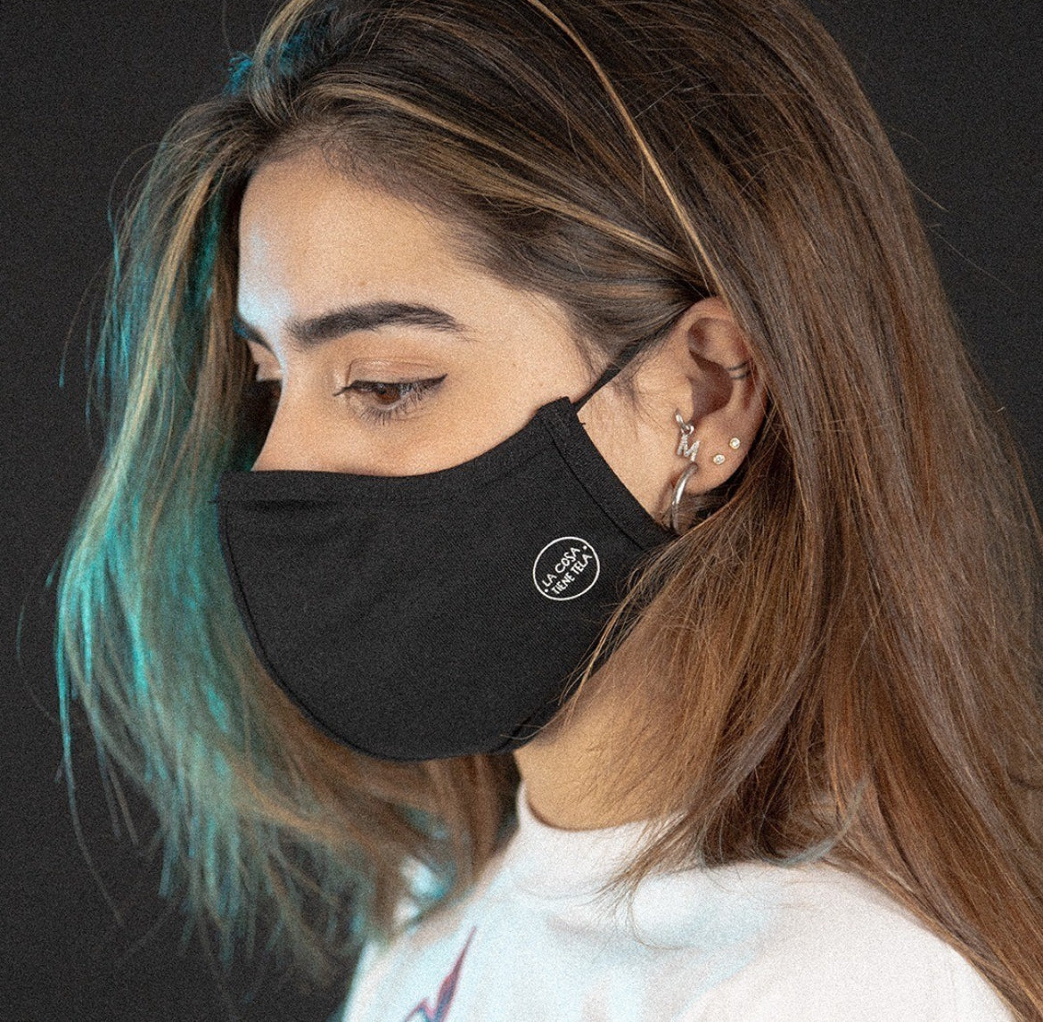 Foto de chica probándose la mascarilla negra de tela reutilizable, certificada según la norma UNE 0065, combinando protección y estilo.