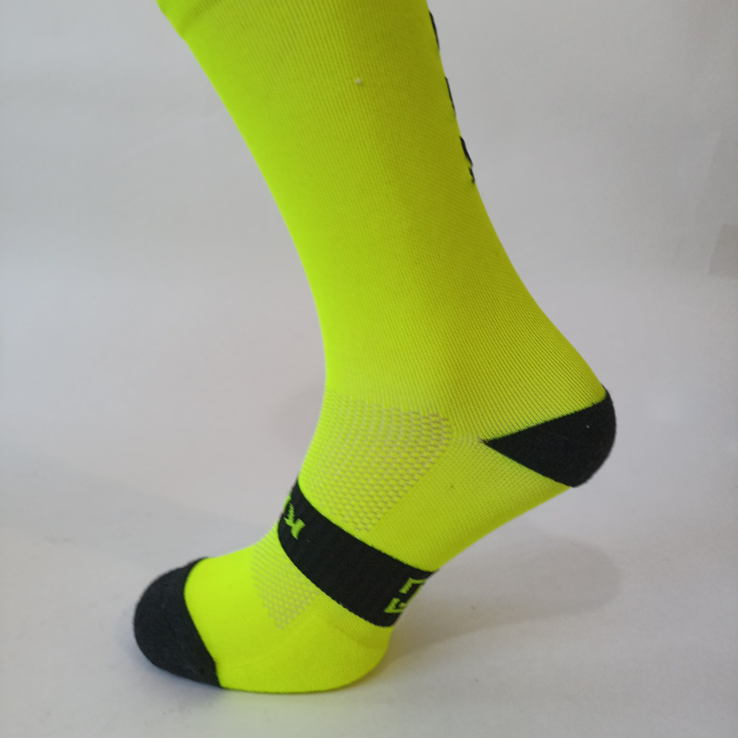 Parte lateral calcetines técnicos de alto rendimiento amarillos, fabricados con materiales termorreguladores que ofrecen transpirabilidad, soporte y comodidad durante actividades físicas intensas.