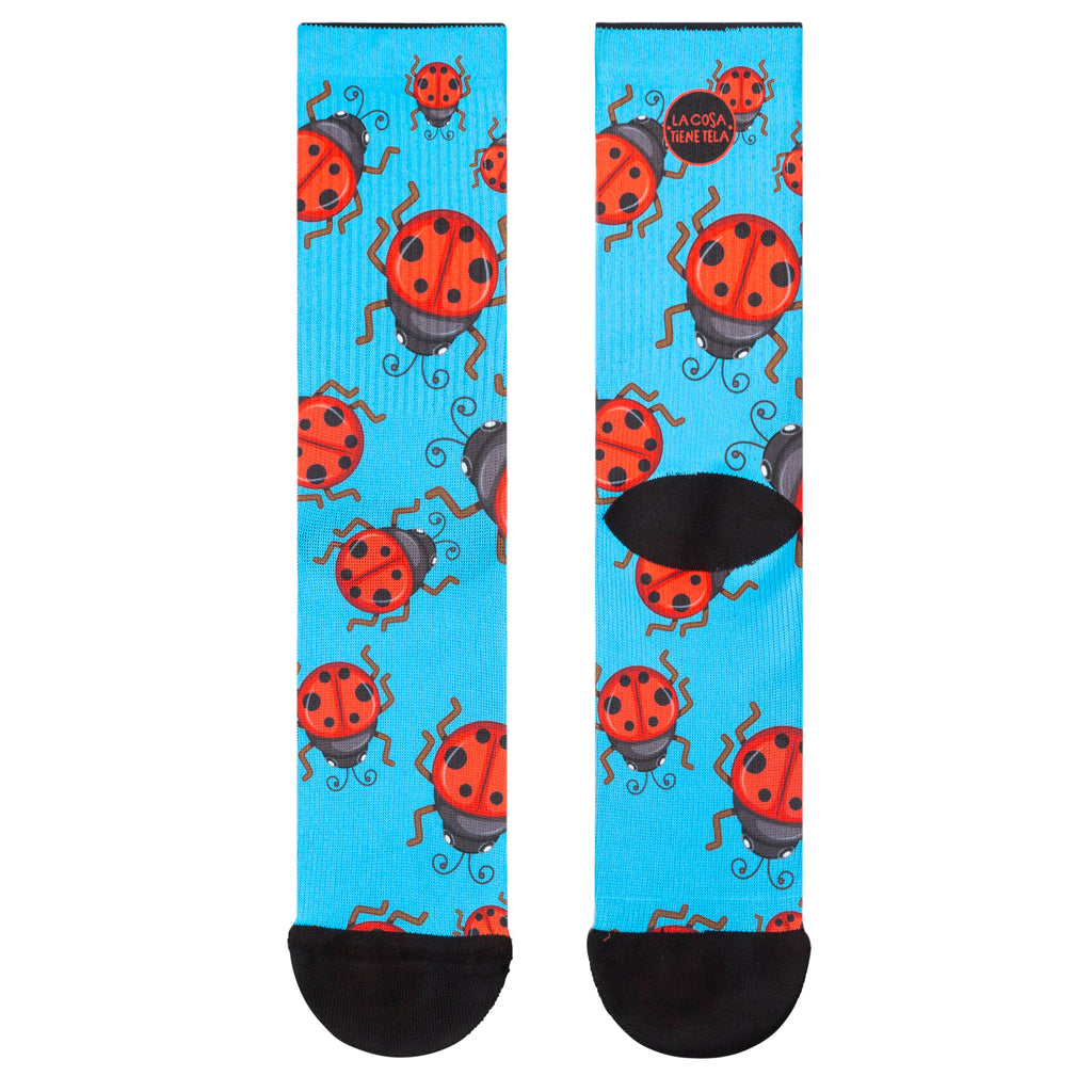 Parte delantera y trasera de los calcetines azules con estampado de mariquitas rojas, ideales para añadir un toque natural y colorido a tu atuendo.